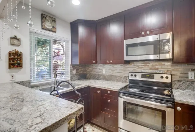 a kitchen with stainless steel appliances granite countertop wooden cabinets and a stove top oven