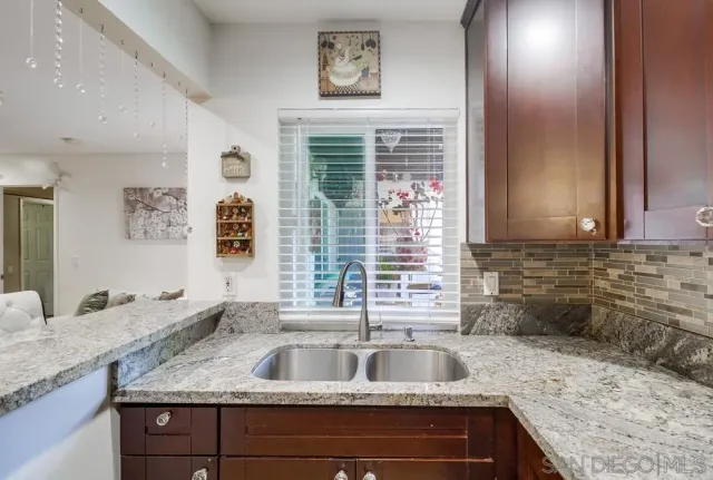 a kitchen with a granite countertop sink and natural light