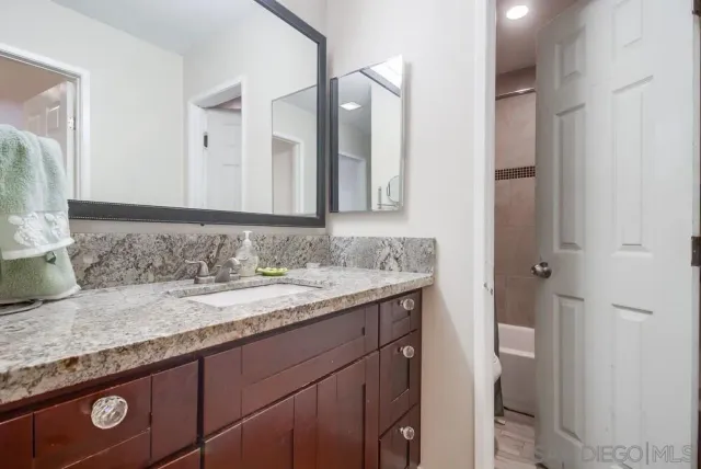 a bathroom with a granite countertop sink and a mirror