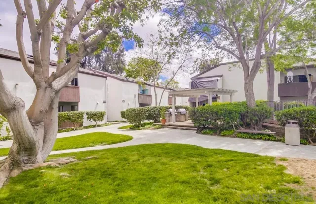 a view of a backyard with table and chairs under a large tree