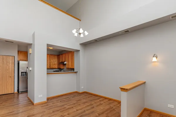 a view of a hallway with wooden floor and a kitchen