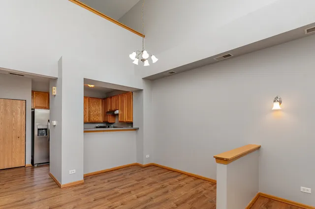 a view of a hallway with wooden floor and a kitchen