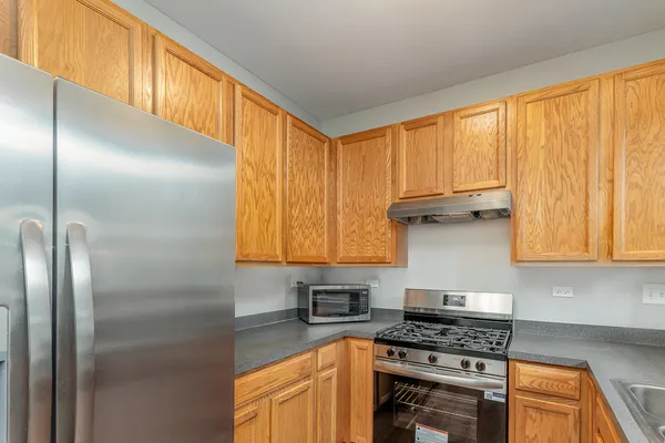 a kitchen with stainless steel appliances granite countertop a refrigerator a stove and a sink