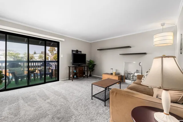 a living room with furniture a flat screen tv and a floor to ceiling window