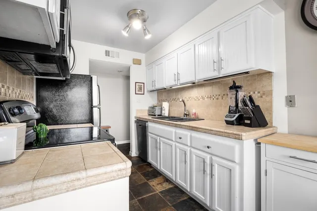 a kitchen with kitchen island granite countertop a sink a stove and refrigerator