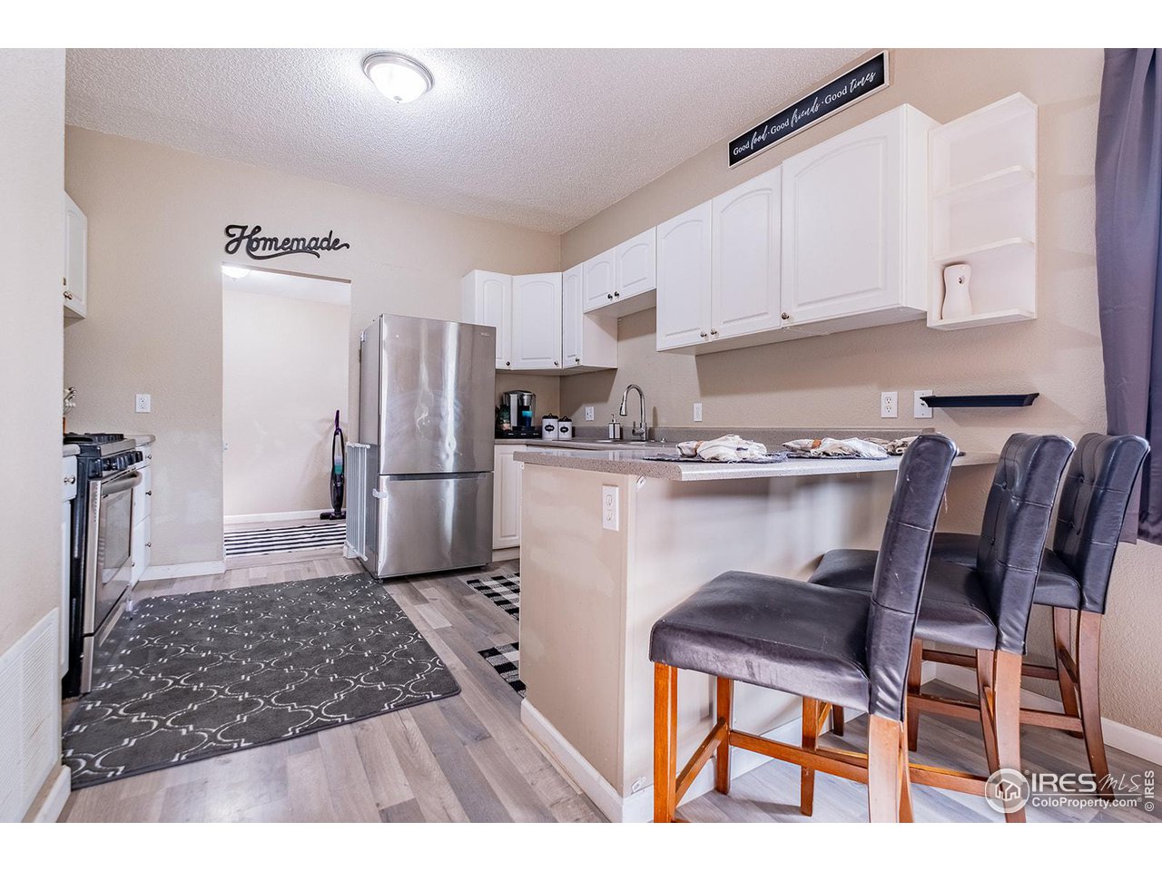 428 Douglas Street Sterling, CO 80751 - Photo 5 of 14 a kitchen with stainless steel appliances granite countertop a refrigerator a stove a sink dishwasher and white cabinets with wooden floor