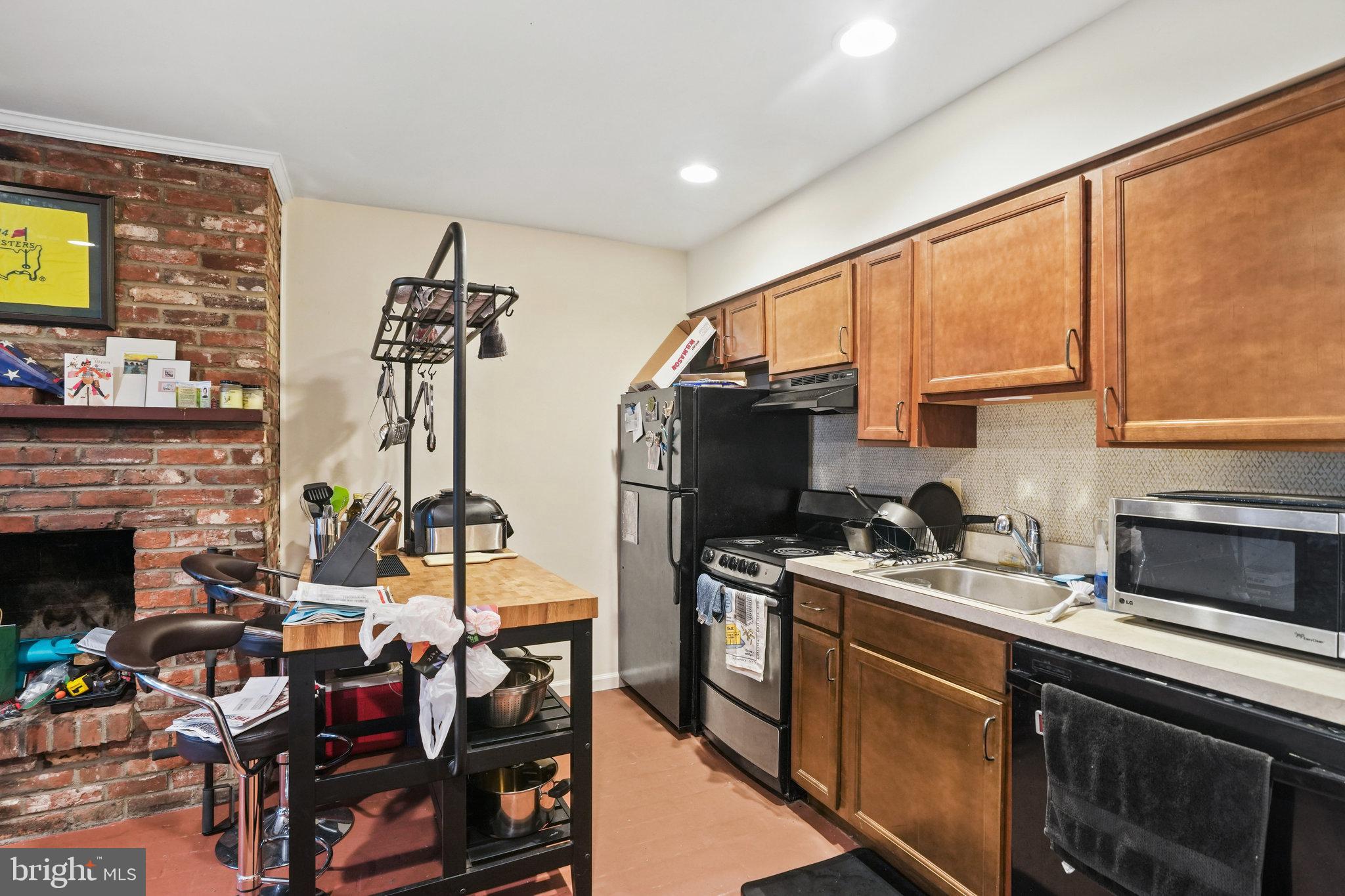 628 A Street Northeast Washington, DC 20002 - Photo 22 of 29 a kitchen with stainless steel appliances a stove a sink dishwasher and a fireplace with wooden floor