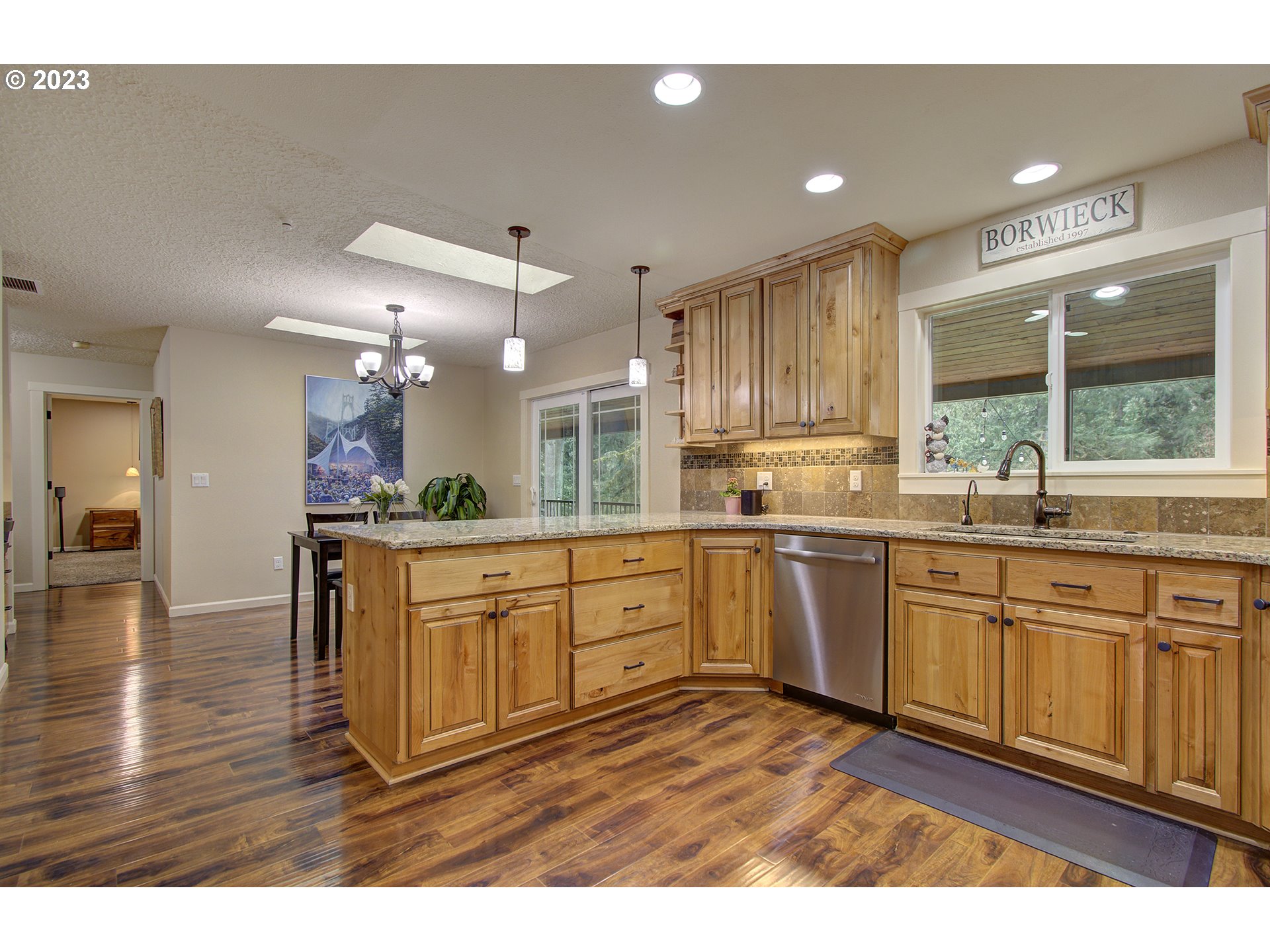 13025 Northeast Prairie Road Brush Prairie, WA 98606 - Photo 8 of 47 a large kitchen with kitchen island granite countertop a stove a sink a refrigerator and white cabinets with wooden floor