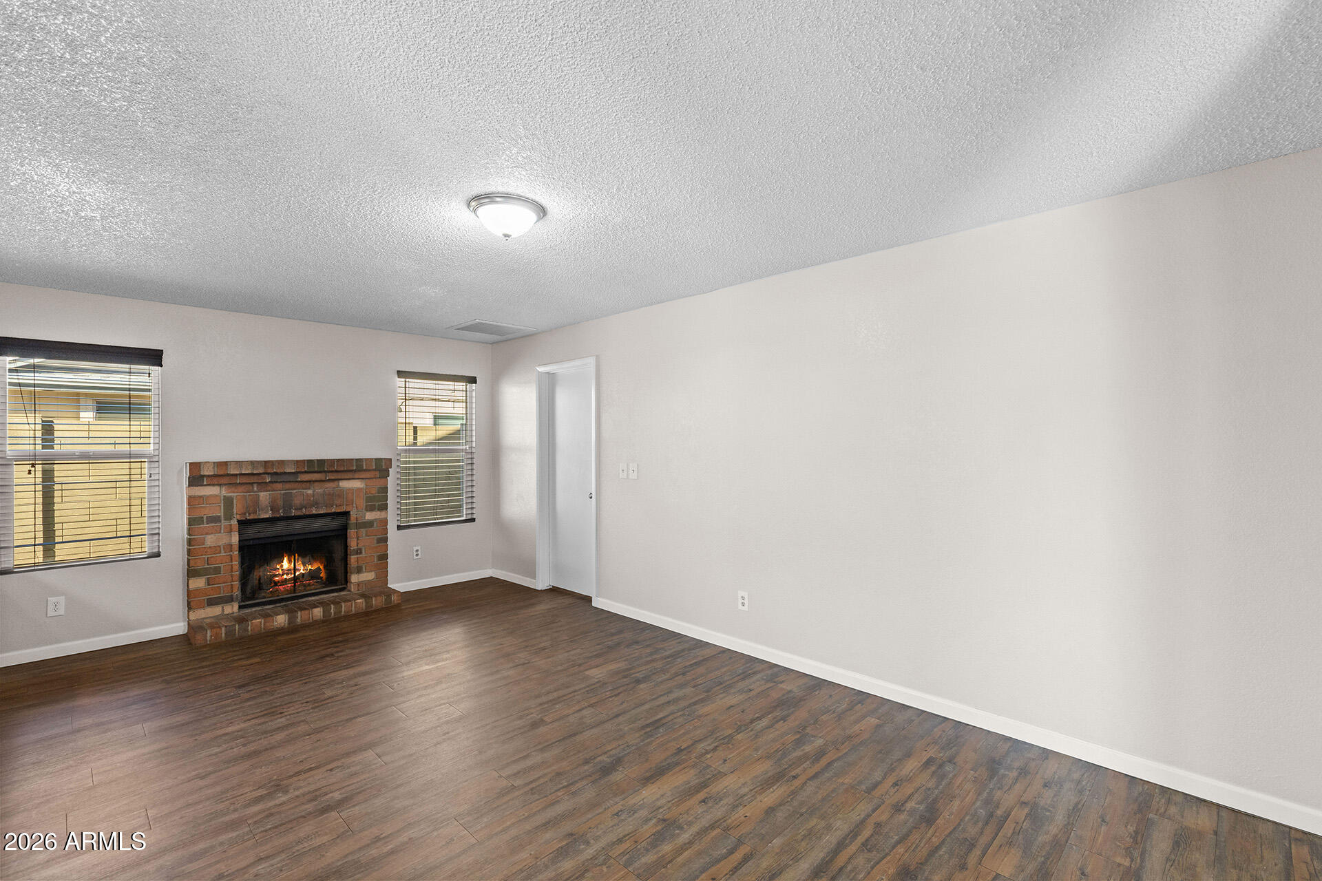7267 West Charter Oak Road Peoria, AZ 85381 - Photo 12 of 45 an empty room with wooden floor fireplace and windows