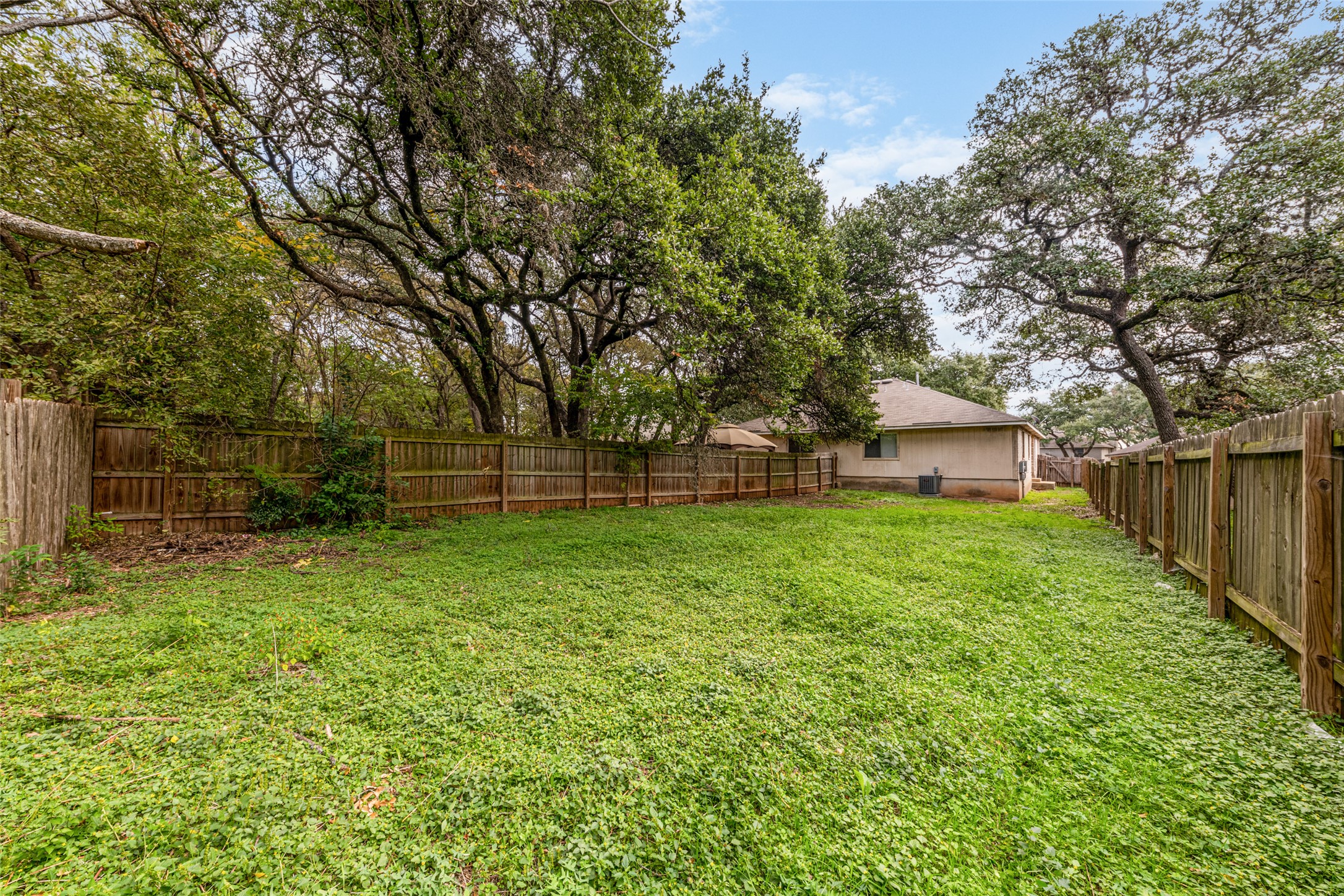 7216 Aldea Drive, Unit A Austin, TX 78745 - Photo 25 of 25 Expansive backyard featuring a lush lawn, wood privacy fencing, and mature trees providing natural shading