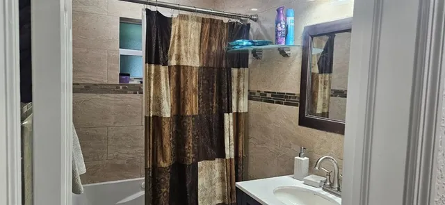 a bathroom with a tub sink and mirror