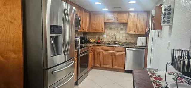 a kitchen with stainless steel appliances granite countertop a refrigerator sink and microwave