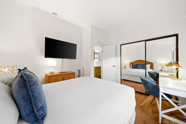 a bedroom with a bed and a flat tv screen on the dresser