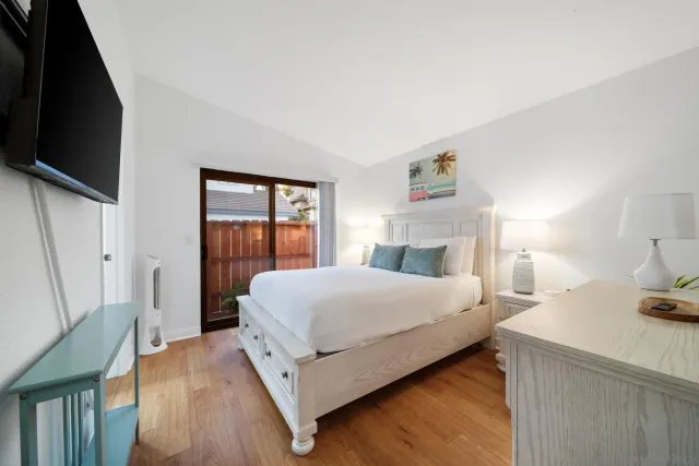 a bedroom with a bed and a flat tv screen on a dresser