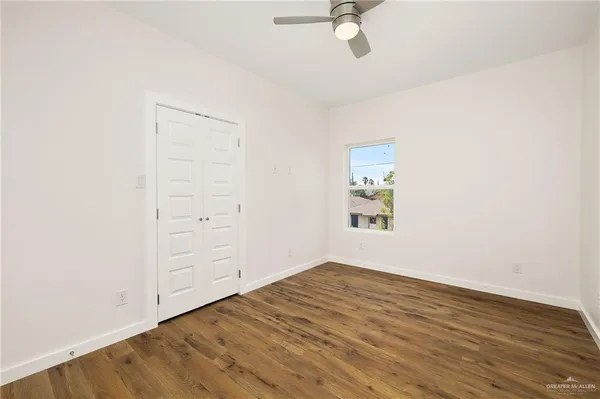 an empty room with wooden floor closet and windows