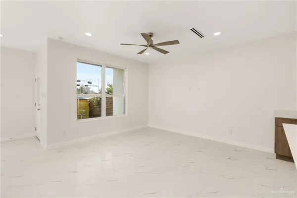 an empty room with chandelier fan and windows