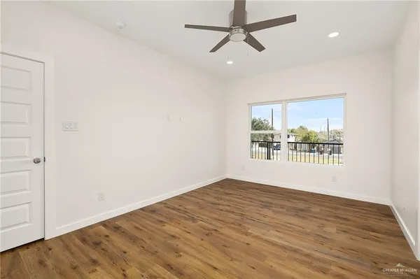 an empty room with wooden floor and windows