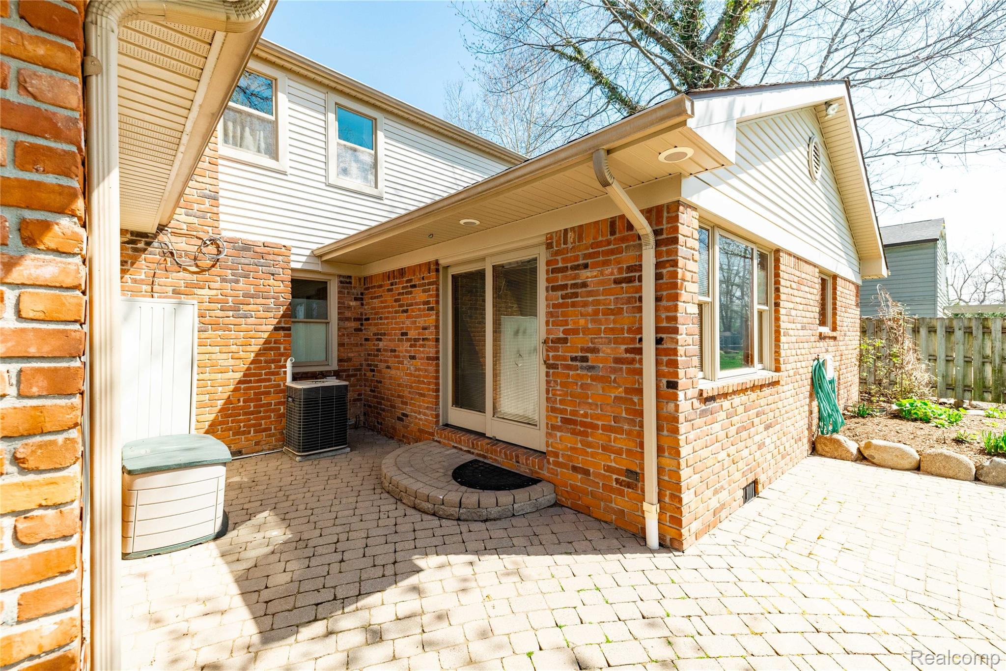 7611 Ferry Road Grosse Ile, MI 48138 - Photo 47 of 51 Paver patio featuring a circular stone fire pit, brick and siding exterior, sliding glass door, and integrated gutter system