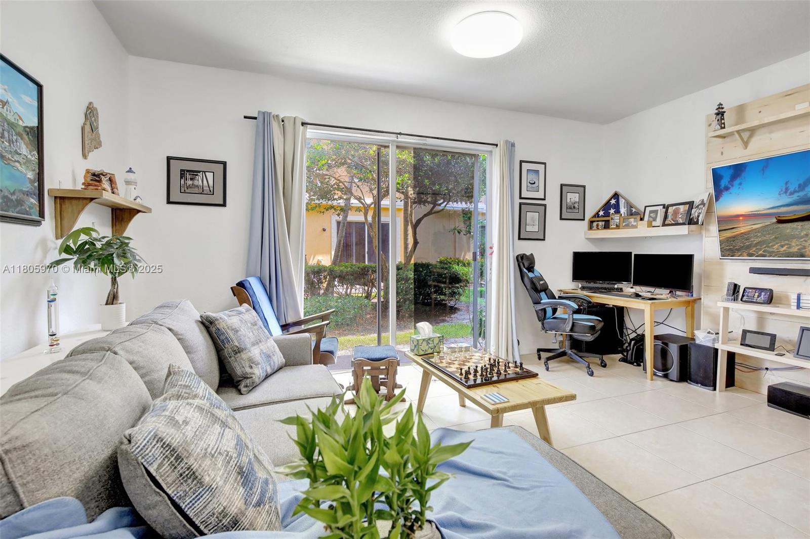 8999 Southwest 18th Street, Unit 1401 Miramar, FL 33025 - Photo 32 of 51 a living room with furniture a flat screen tv and a large window