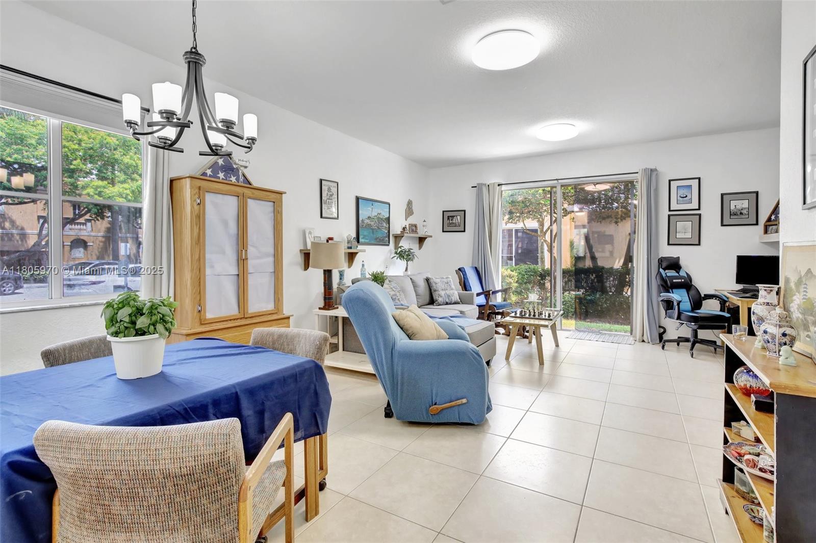 8999 Southwest 18th Street, Unit 1401 Miramar, FL 33025 - Photo 37 of 51 a living room with furniture a chandelier and a dining table