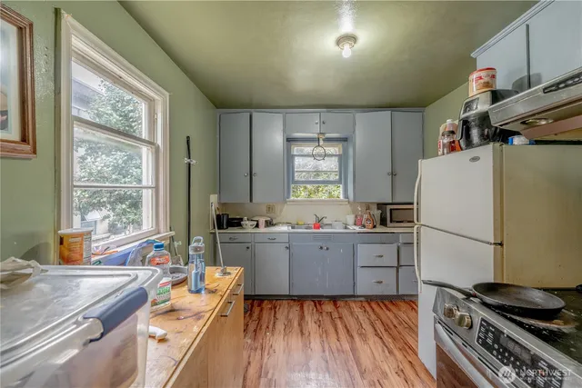 a kitchen with a refrigerator a stove a sink dishwasher and wooden cabinets with wooden floor