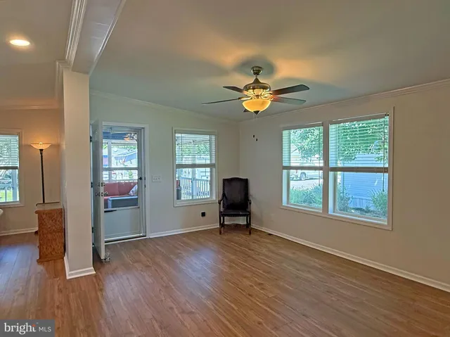a view of an empty room with a window and wooden floor