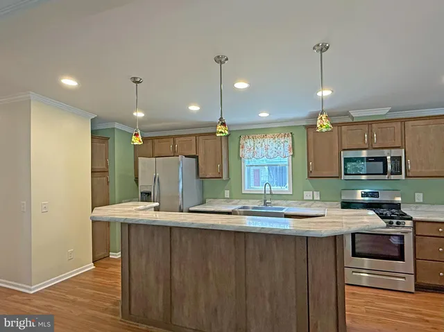 a kitchen with stainless steel appliances a stove top oven a refrigerator and a fireplace