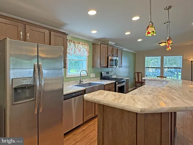a kitchen with kitchen island granite countertop a sink cabinets and stainless steel appliances