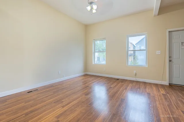an empty room with wooden floor and windows
