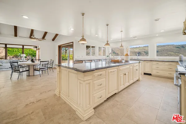 a kitchen with stainless steel appliances kitchen island granite countertop a table chairs sink and cabinets