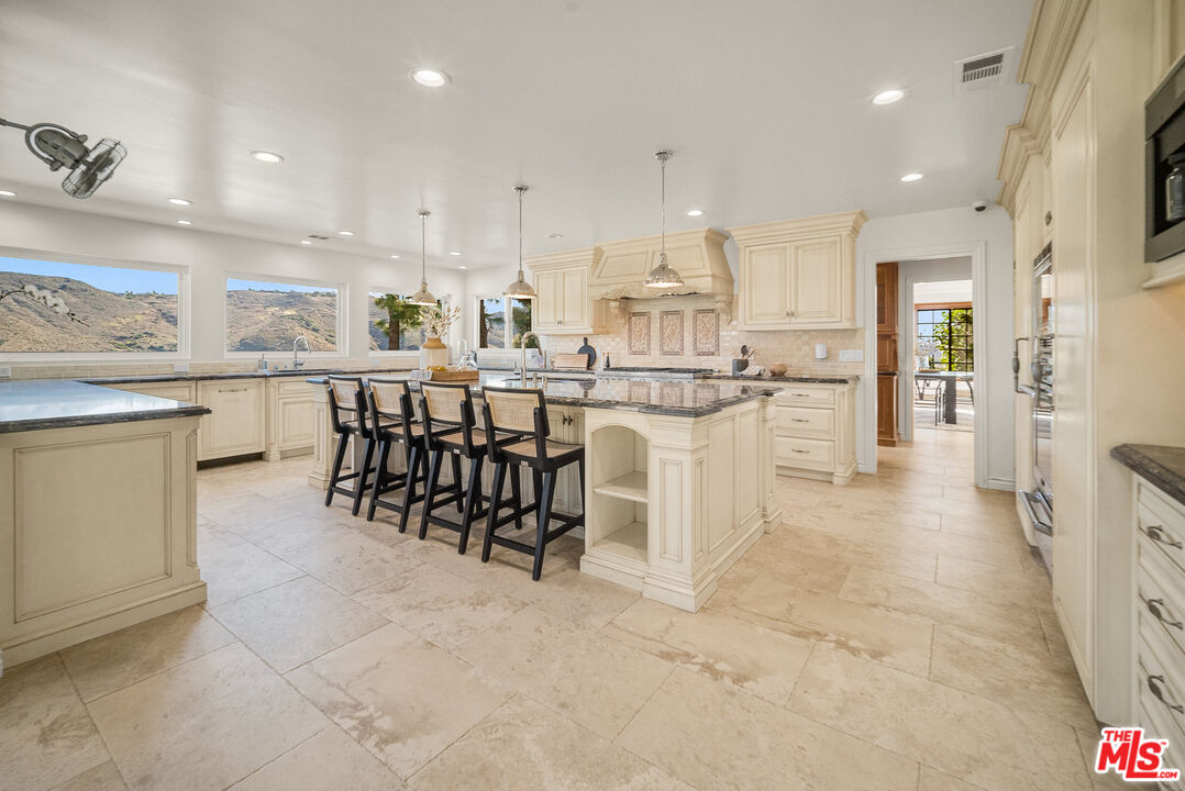 11875 Pradera Road Santa Rosa Valley, CA 93012 - Photo 16 of 35 a kitchen with stainless steel appliances kitchen island granite countertop a table chairs sink and cabinets