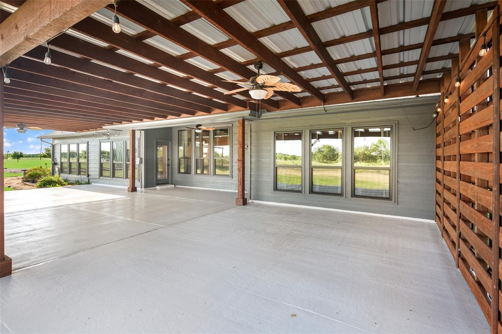 1019 Vaughan Lane Tioga, TX 76271 - Photo 34 of 40 Expansive covered patio featuring a large concrete surface, exposed wood beam ceiling, metal roof, and a decorative wood privacy screen