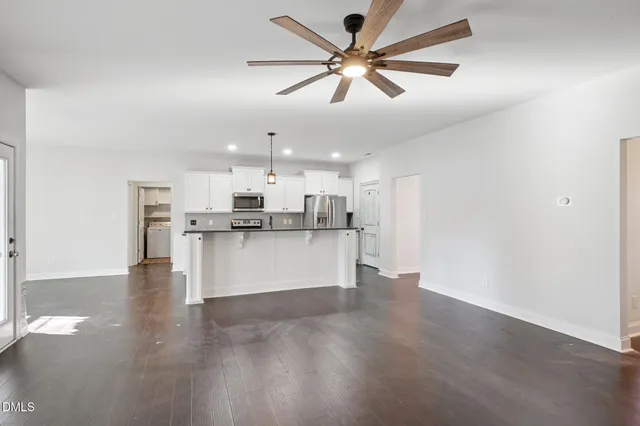 a kitchen with stainless steel appliances granite countertop a refrigerator a stove a sink dishwasher and a microwave with wooden floor