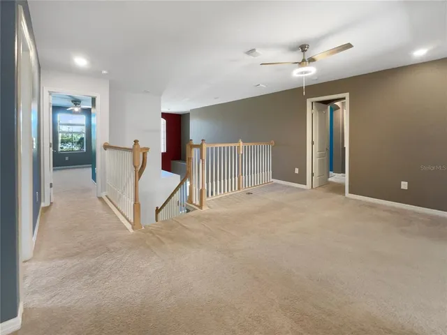 a view of an empty room with stairs and a ceiling fan
