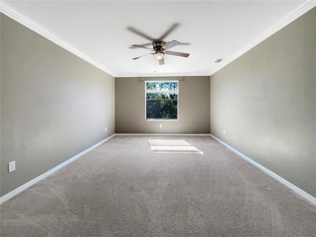 an empty room with windows and ceiling fan