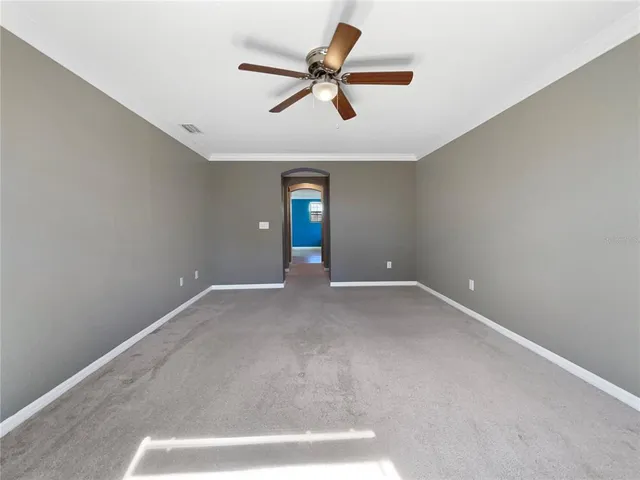 an empty room with ceiling fan and window