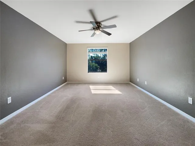 an empty room with windows and ceiling fan