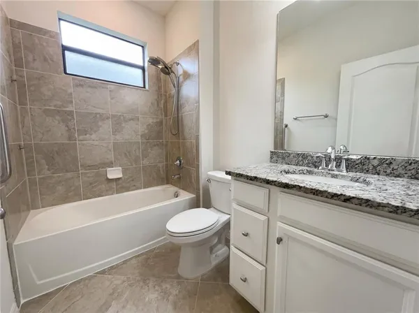 a bathroom with a granite countertop sink toilet mirror and bathtub