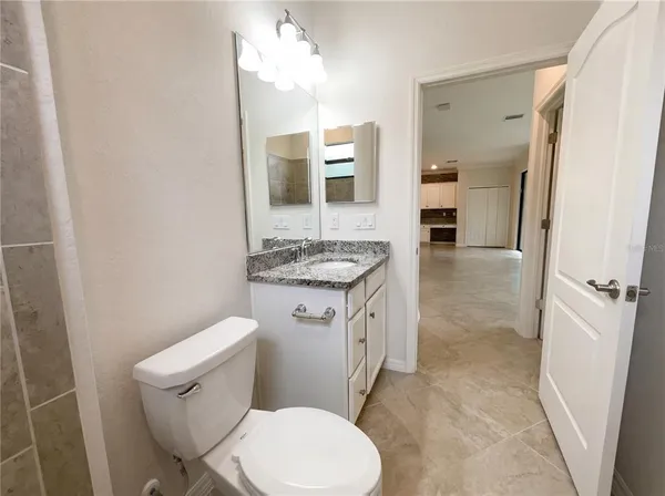 a bathroom with a granite countertop toilet sink and mirror