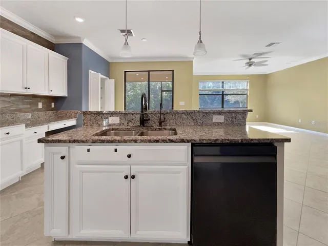 a kitchen with granite countertop a sink cabinets and wooden floor