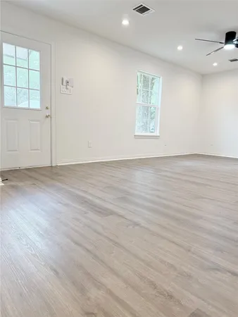 an empty room with wooden floor and windows