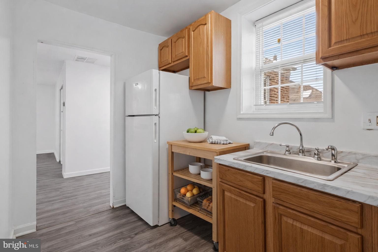 4834-4836 Sheriff Road Northeast Washington, DC 20019 - Photo 13 of 18 a kitchen with stainless steel appliances granite countertop a sink and a white cabinets with wooden floor