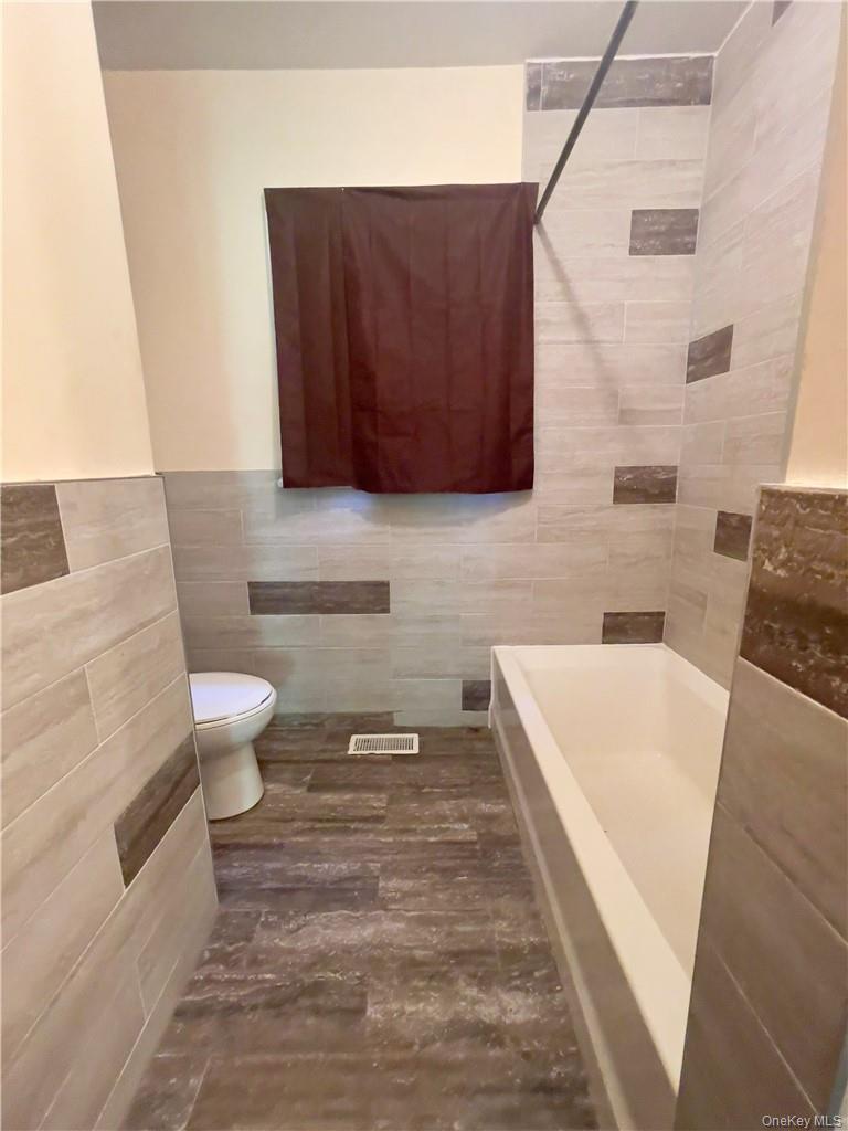 4 Old Turnpike Road Bloomingburg, NY 12721 - Photo 14 of 27 Bathroom featuring tiled shower / bath, tile walls, and toilet
