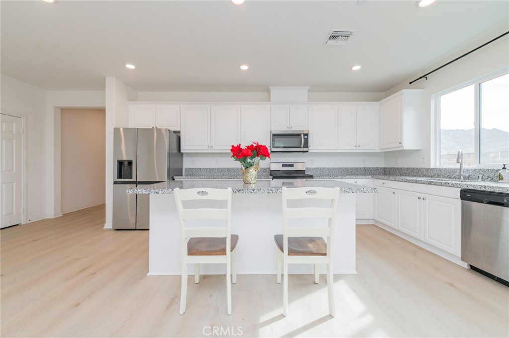 7309 Grazing Lane Riverside, CA 92507 - Photo 24 of 43 a kitchen with stainless steel appliances kitchen island granite countertop a table and chair