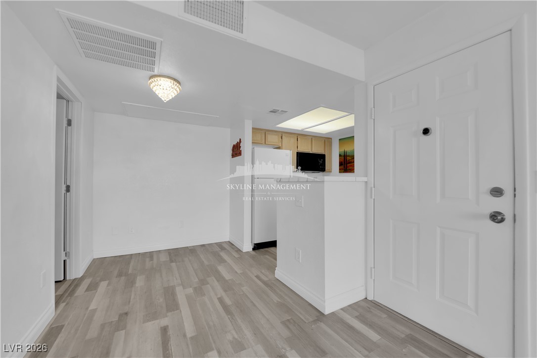 8070 West Russell Road, Unit 2063 Las Vegas, NV 89113 - Photo 11 of 31 Kitchen featuring freestanding refrigerator, light countertops, light brown cabinets, light wood-type flooring, and black microwave