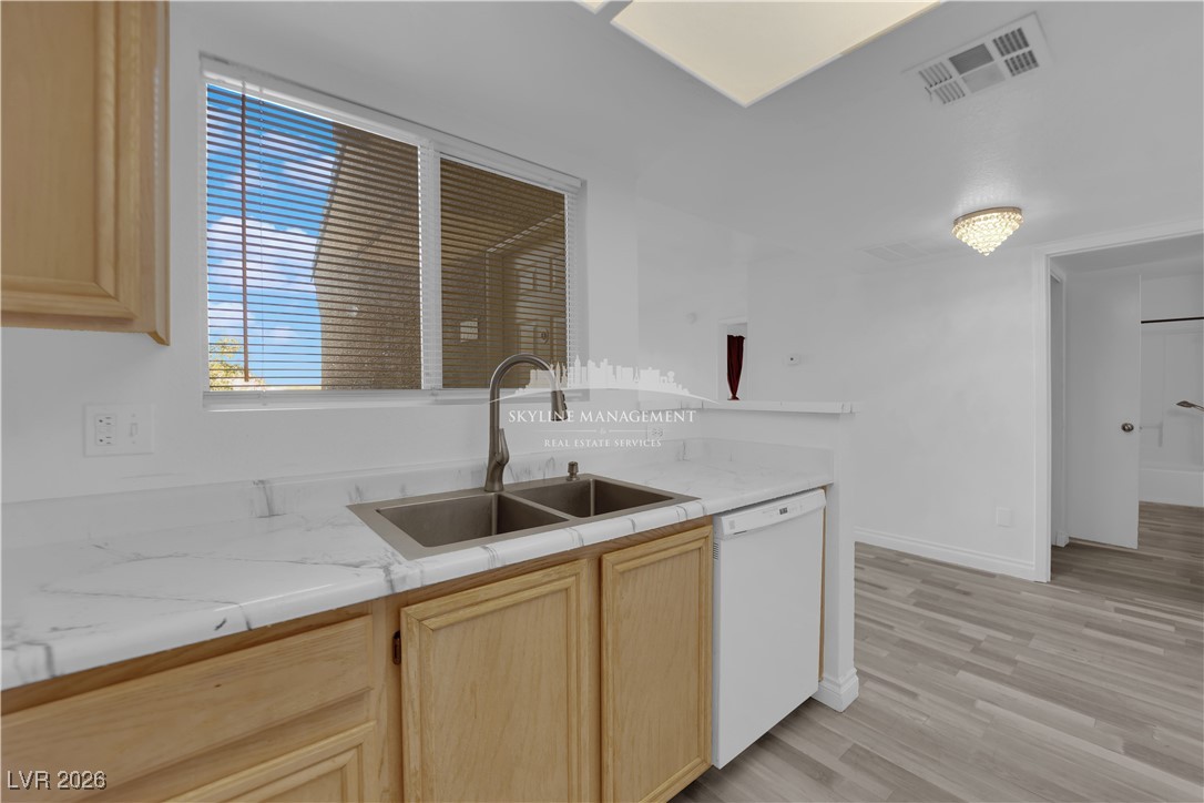 8070 West Russell Road, Unit 2063 Las Vegas, NV 89113 - Photo 16 of 31 Kitchen with light brown cabinetry, dishwasher, light wood finished floors, and light stone countertops