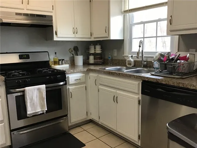 a kitchen with granite countertop white cabinets and black appliances