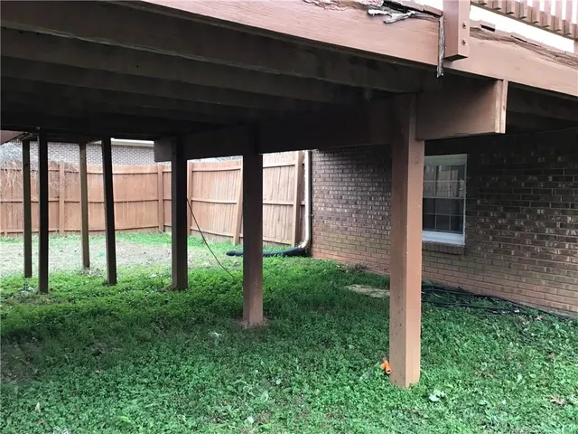 a view of a backyard with plants and large trees