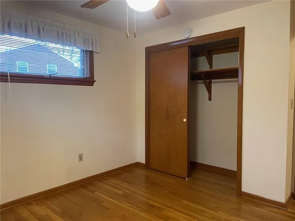 an empty room with wooden floor and a ceiling fan
