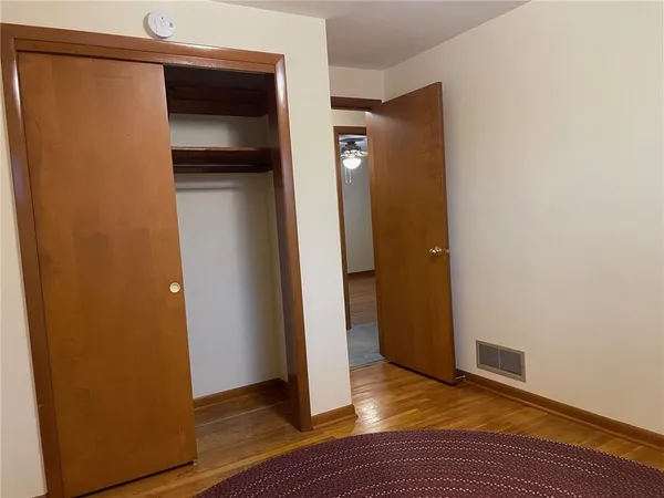 a view of an empty room with wooden floor and closet